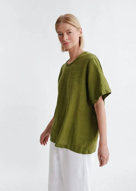 Woman wearing a green oversized shirt and white pants on a white background
