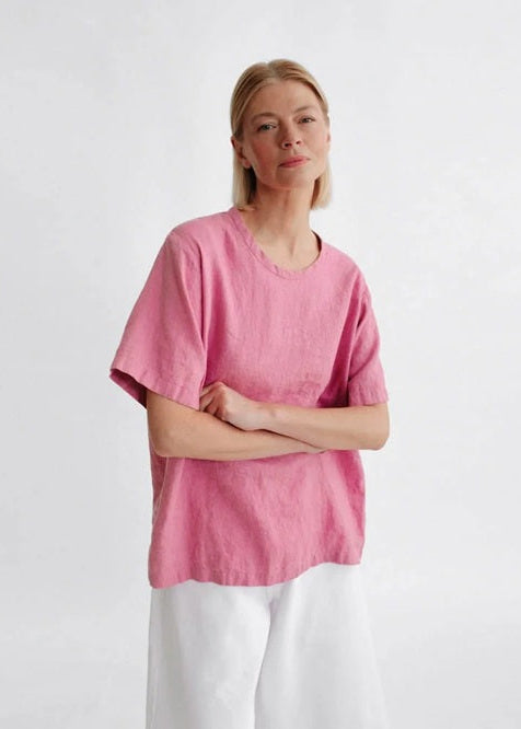 Person wearing a pink shirt and white pants on a light gray background