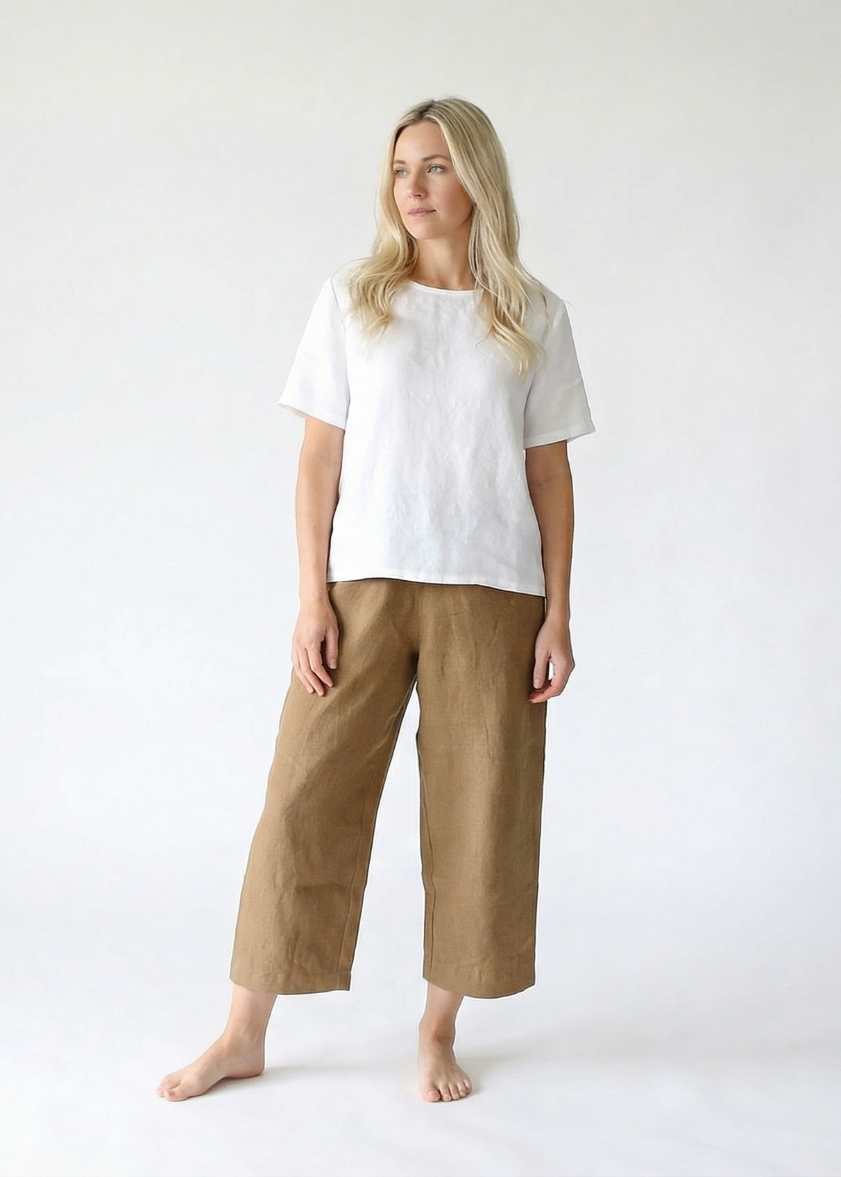 Woman wearing a white shirt and beige pants on a white background