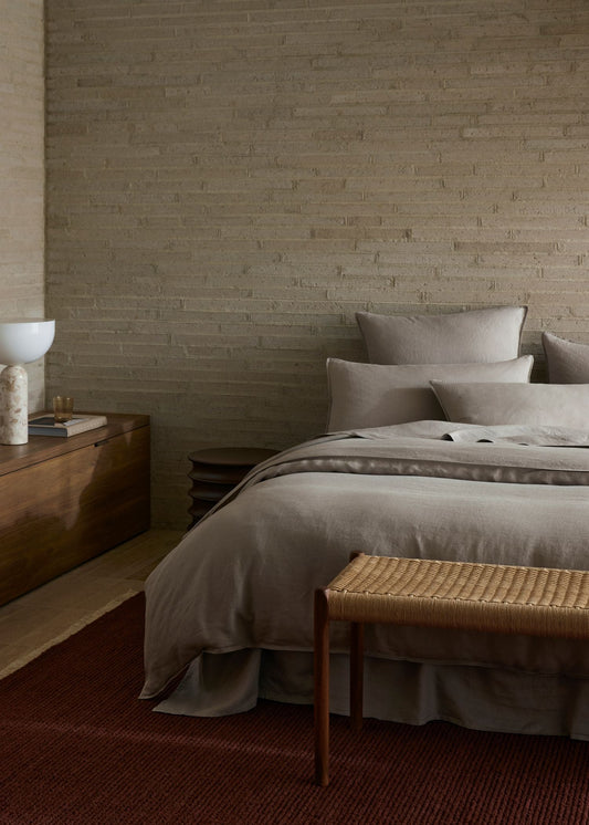 Bedroom with neutral tones, wooden nightstands, and a textured wall.