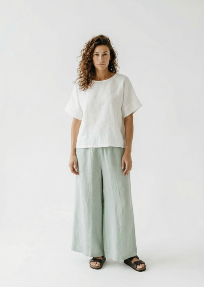 Woman wearing a white top and light green pants on a white background