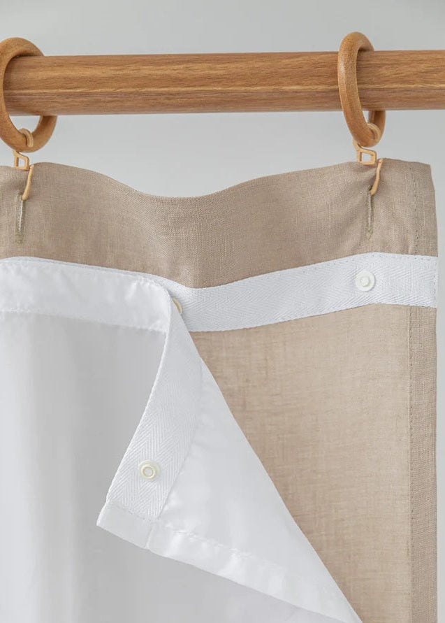 Two shirts, one white and one beige with a white stripe, hanging on a wooden rack.