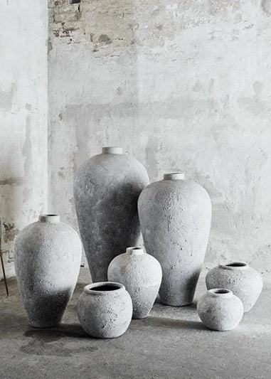 Set of gray ceramic vases against a textured wall.