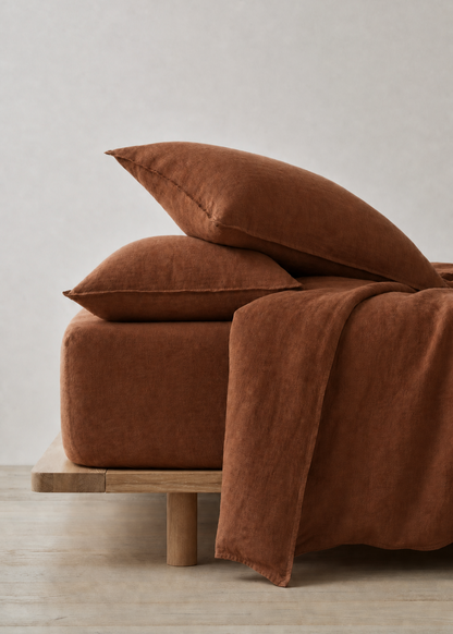 Brown bedspread and pillows on a wooden bed against a light gray wall.