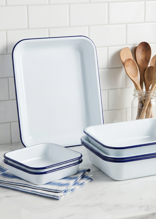 Set of white enameled cookware with blue rims on a kitchen counter.