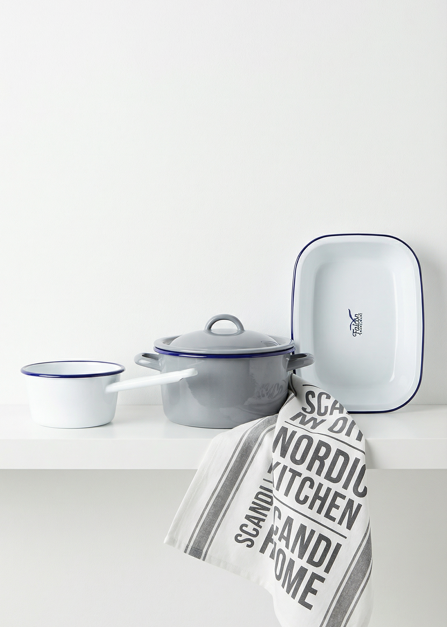 Enamel cookware set with a towel on a white surface