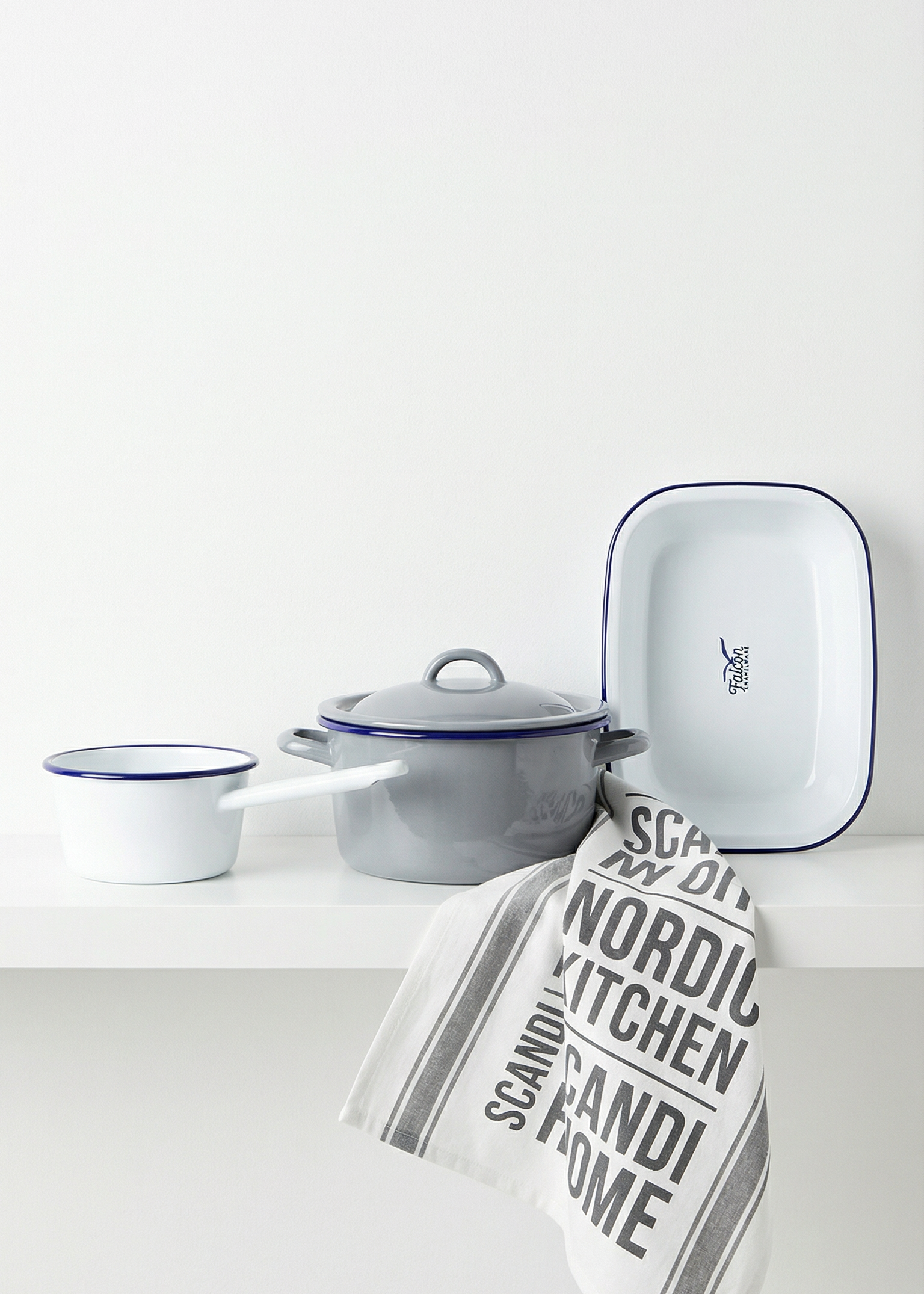 Enamel cookware set with a towel on a white surface