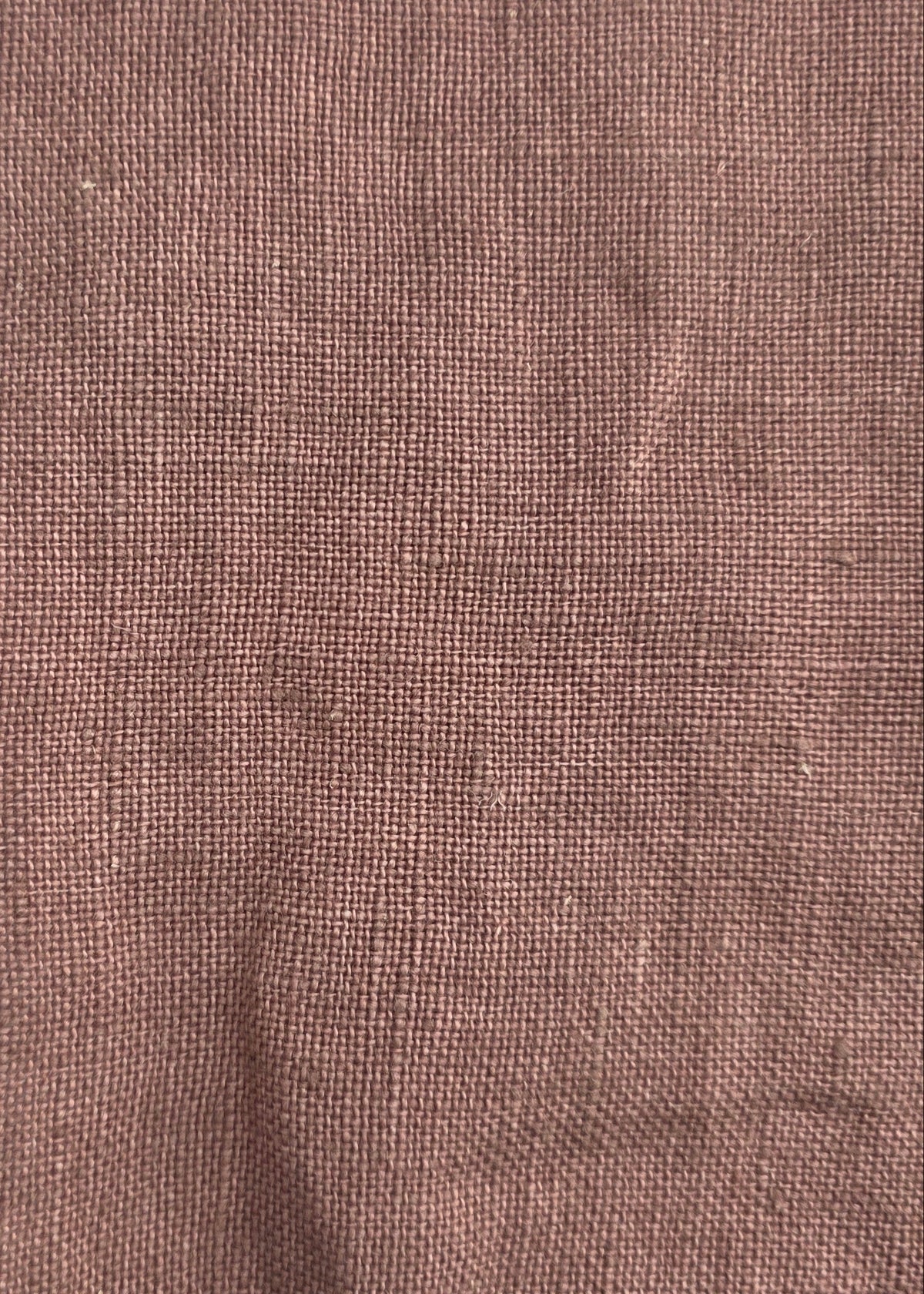 A square piece of textured brown linen fabric with frayed edges, laid flat on a light gray background.