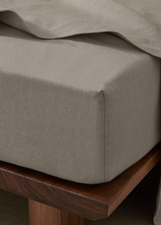 Close-up of a bed with beige bedding and wooden headboard