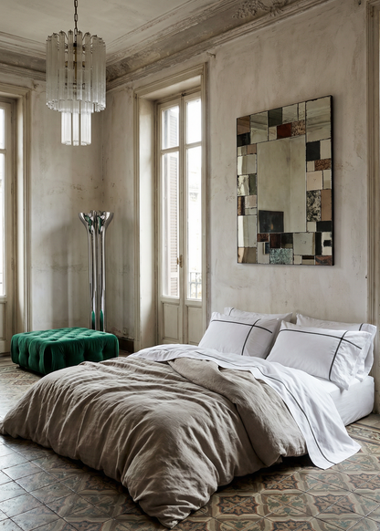 Neatly made bed in a stylish bedroom with a mirror and chandelier.
