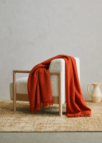 Red blanket draped over a white chair against a neutral background