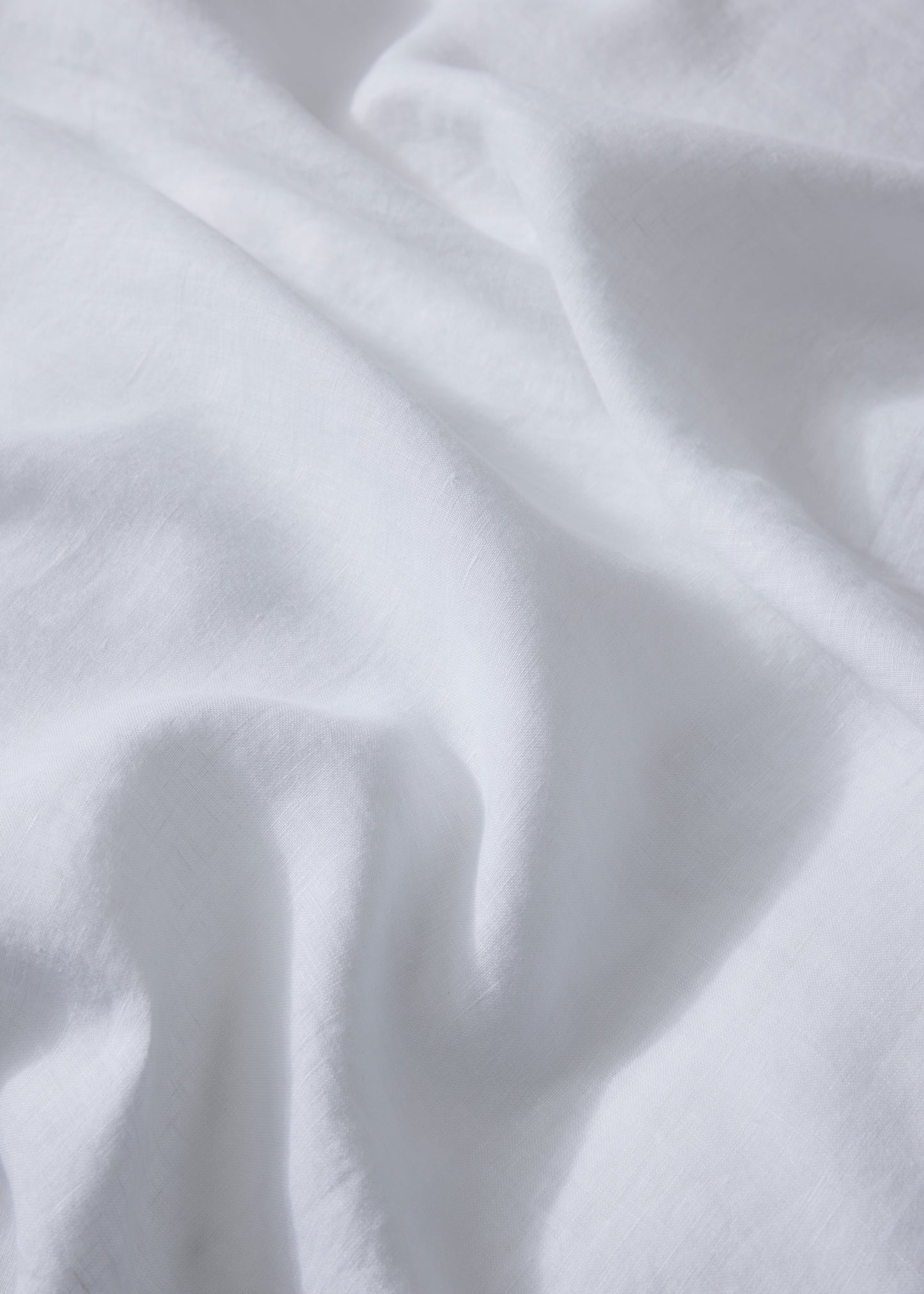 A close-up image of a white linen flat sheet with a plain pattern.