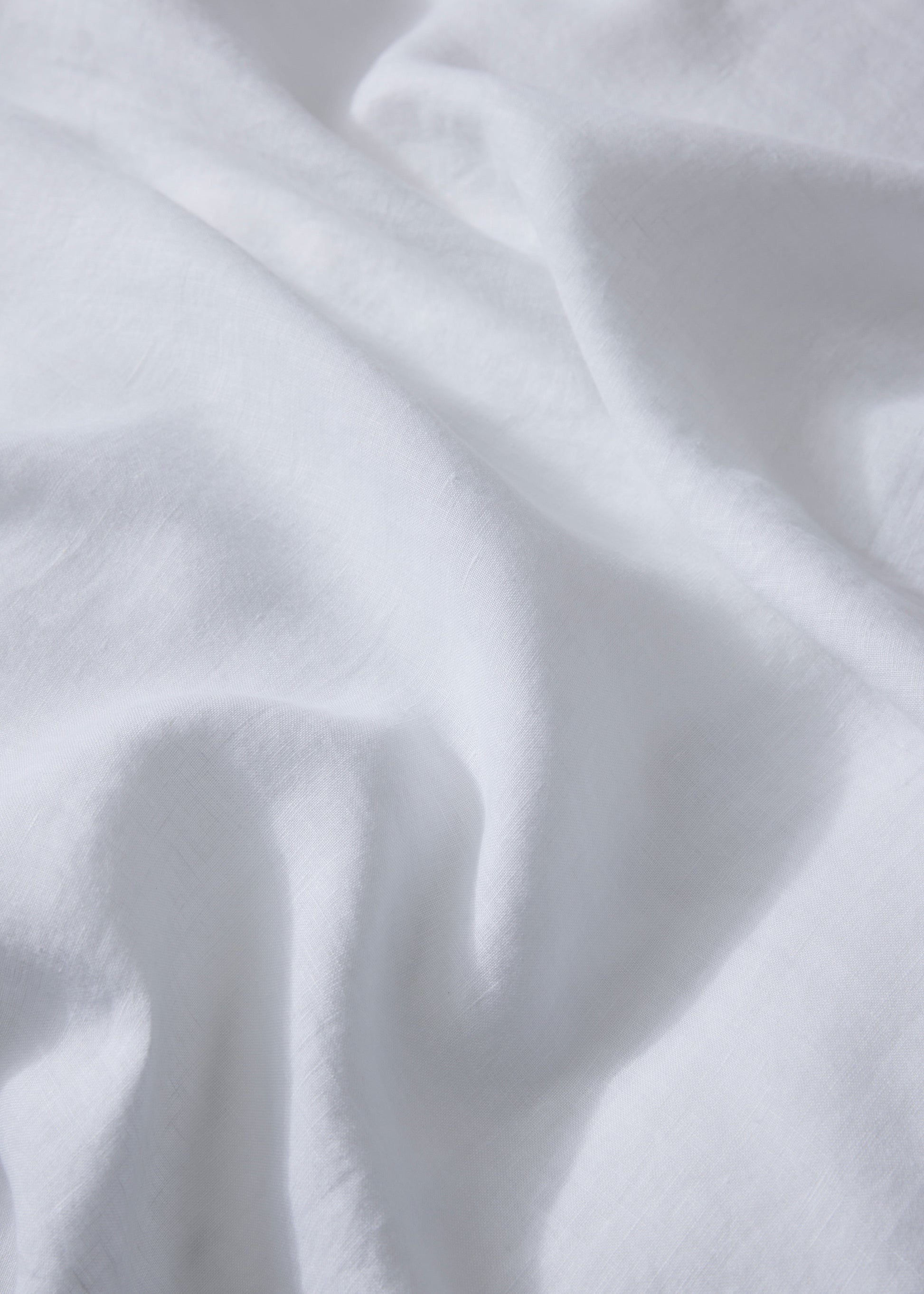A close-up image of a white linen flat sheet with a plain pattern.