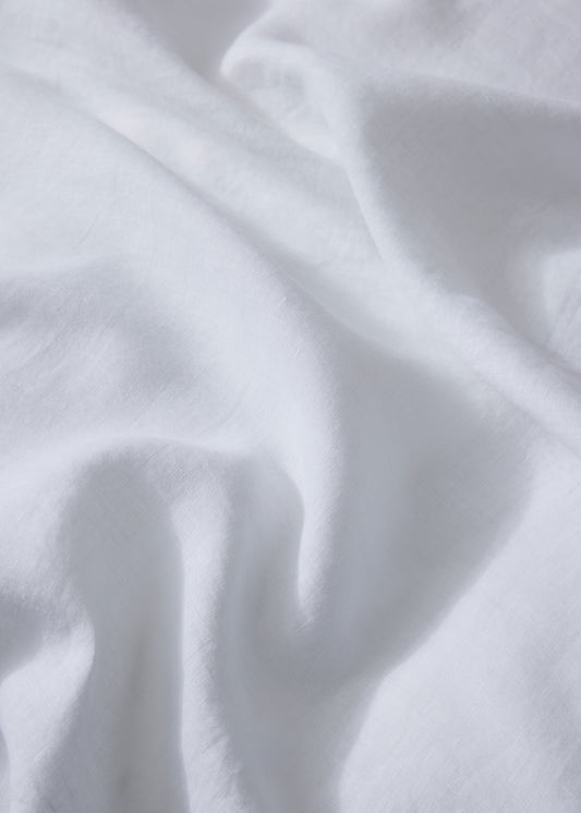 A close-up image of a white linen flat sheet with a plain pattern.