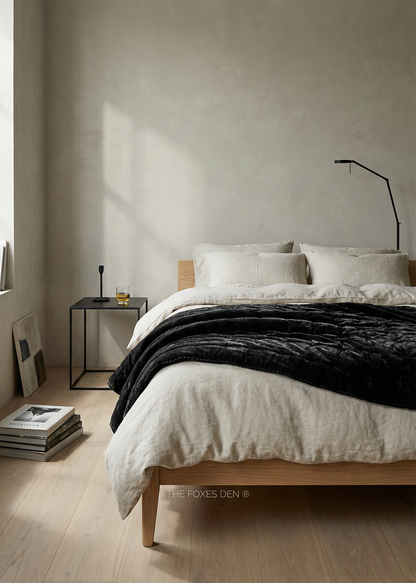 Minimalist bedroom with a bed, side table, and lamp against a plain wall.