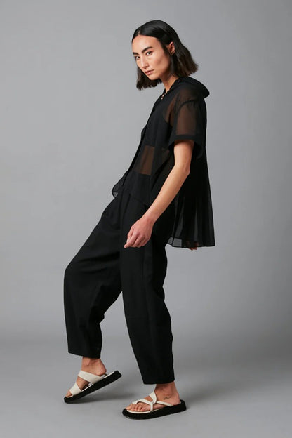 Person wearing a black outfit with sheer sleeves against a gray background