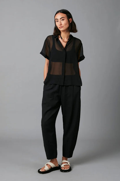 Person wearing a black outfit with sheer top on a gray background