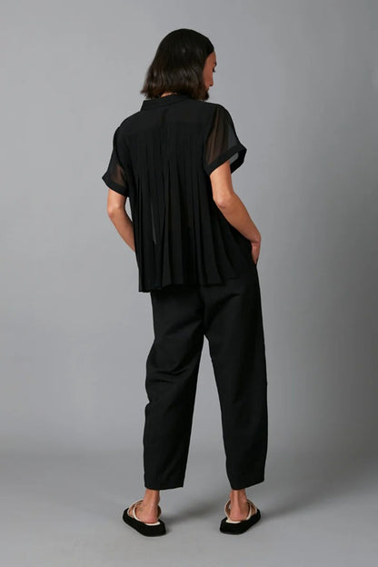 Person wearing a black outfit with sheer sleeves against a gray background