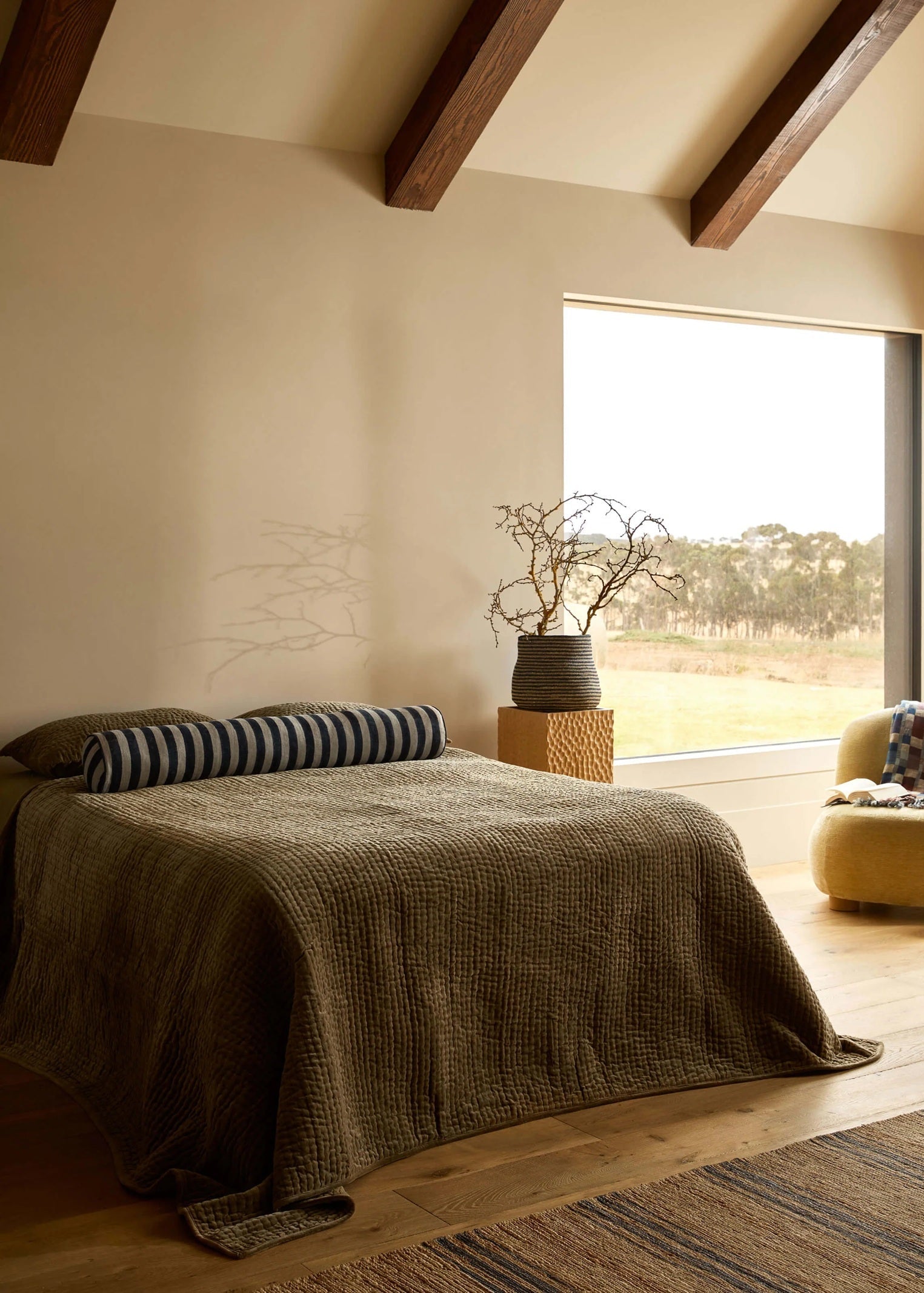 Cozy bedroom with a bed, striped pillow, and large window view.