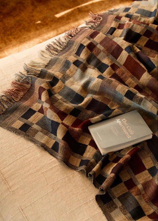 Plaid blanket draped over a surface with a book on top