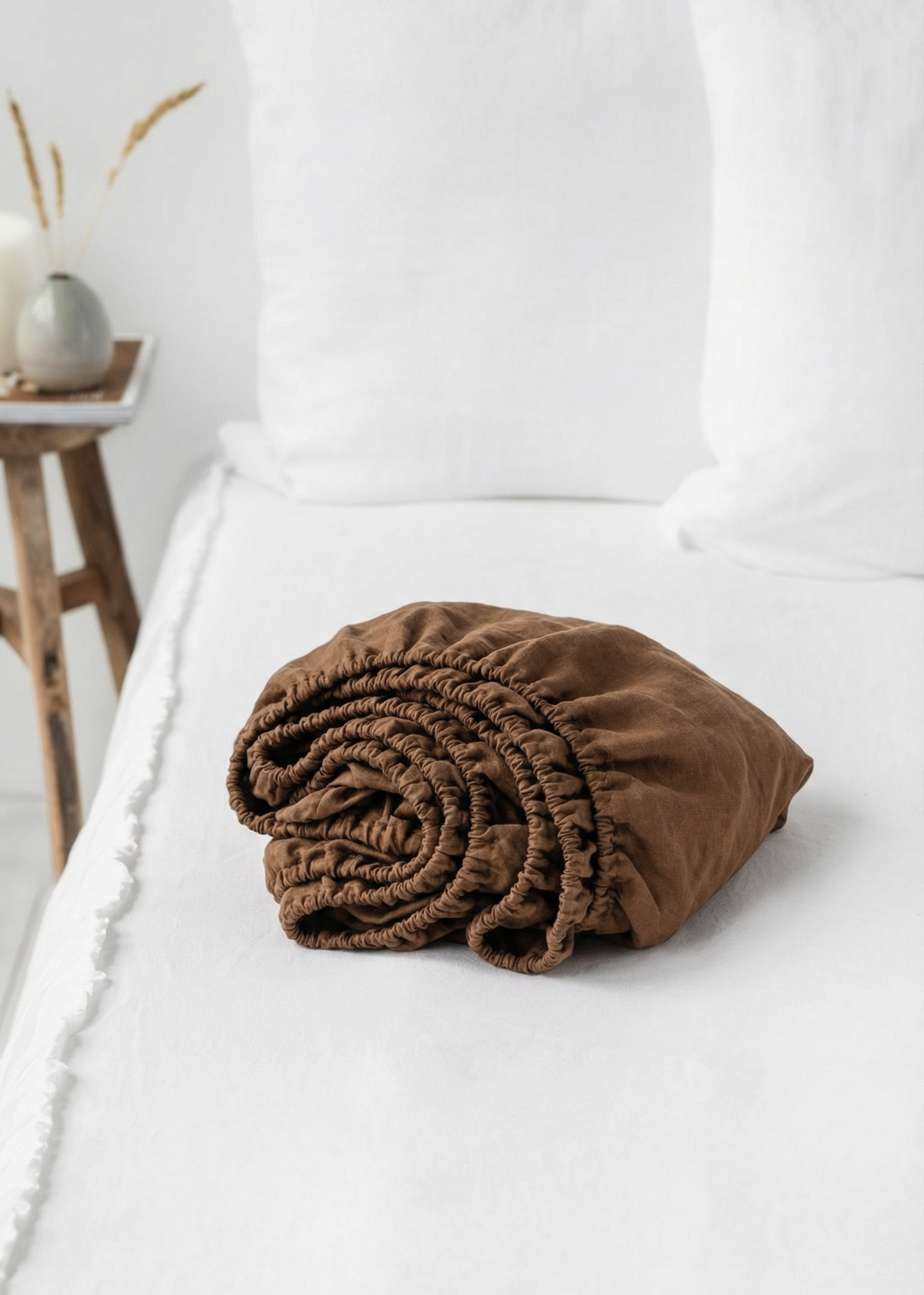 Brown folded blanket on a white bed with a neutral background