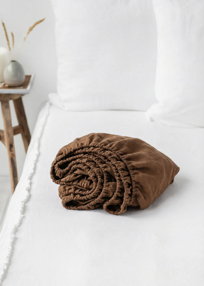 Brown folded blanket on a white bed with a neutral background