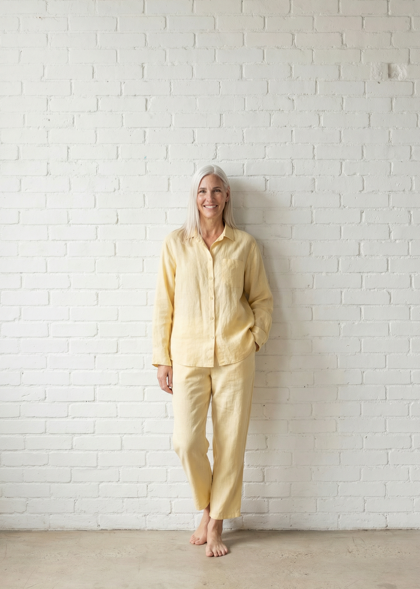 Person wearing a yellow outfit standing against a white brick wall.
