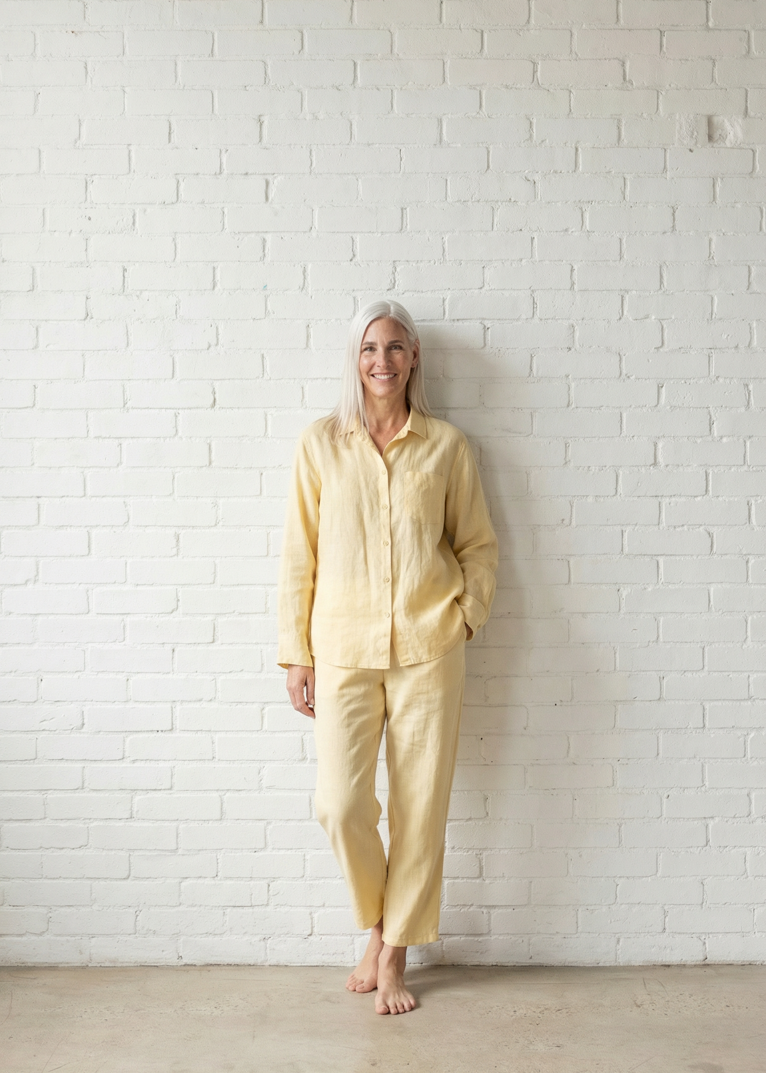 Person wearing a yellow outfit standing against a white brick wall.