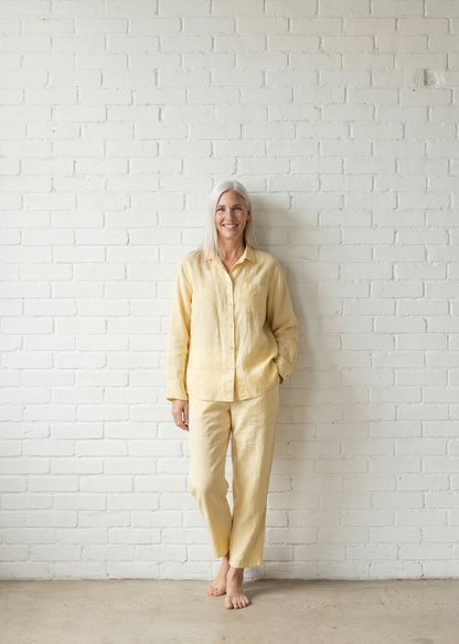 Person wearing a yellow outfit standing against a white brick wall.
