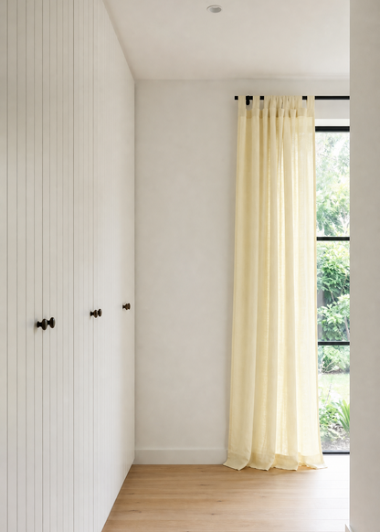 Modern interior with white walls, wooden floor, and a curtain.