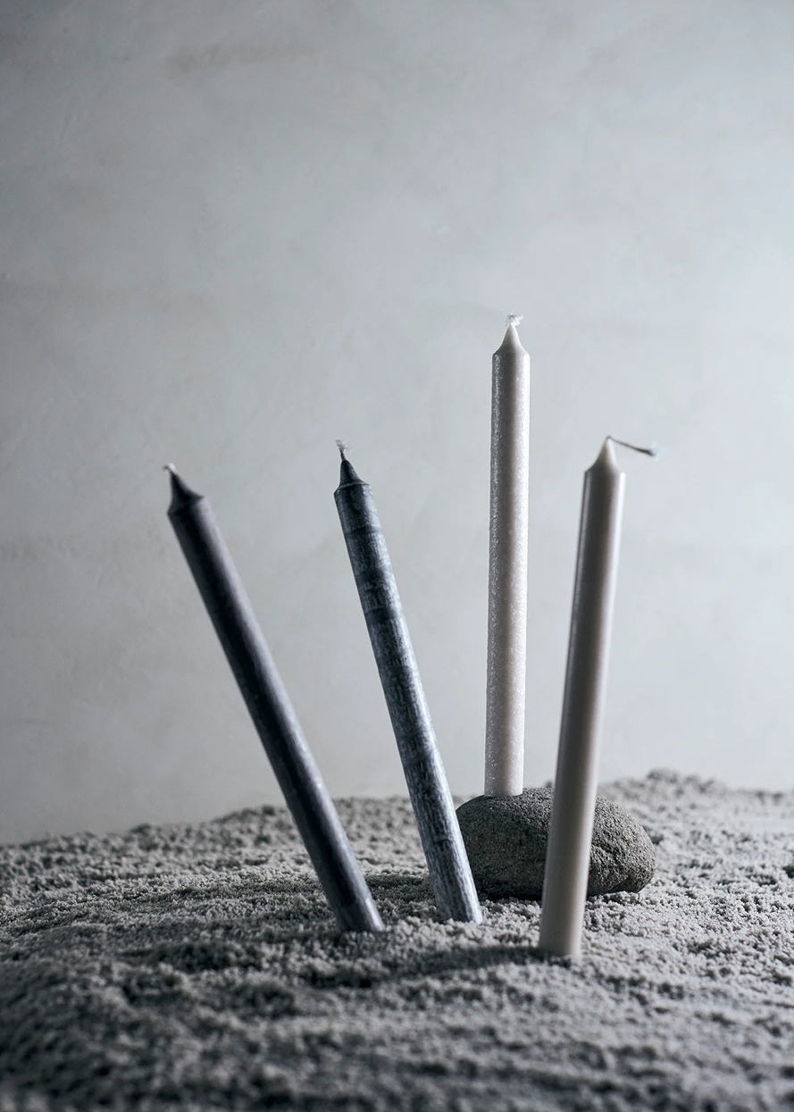 Four candles of varying heights on a textured surface with a neutral background