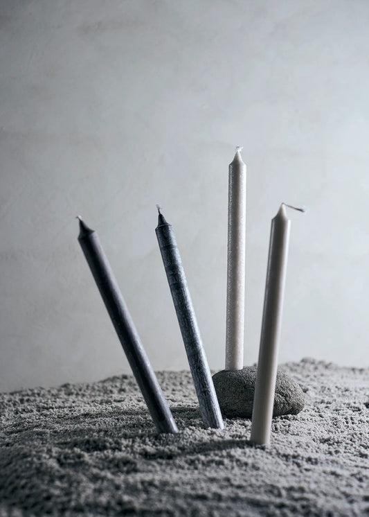 Four candles of varying heights on a textured surface with a neutral background