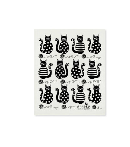 A white dish cloth with a black and polka dot pattern featuring various stylized cat shapes.
