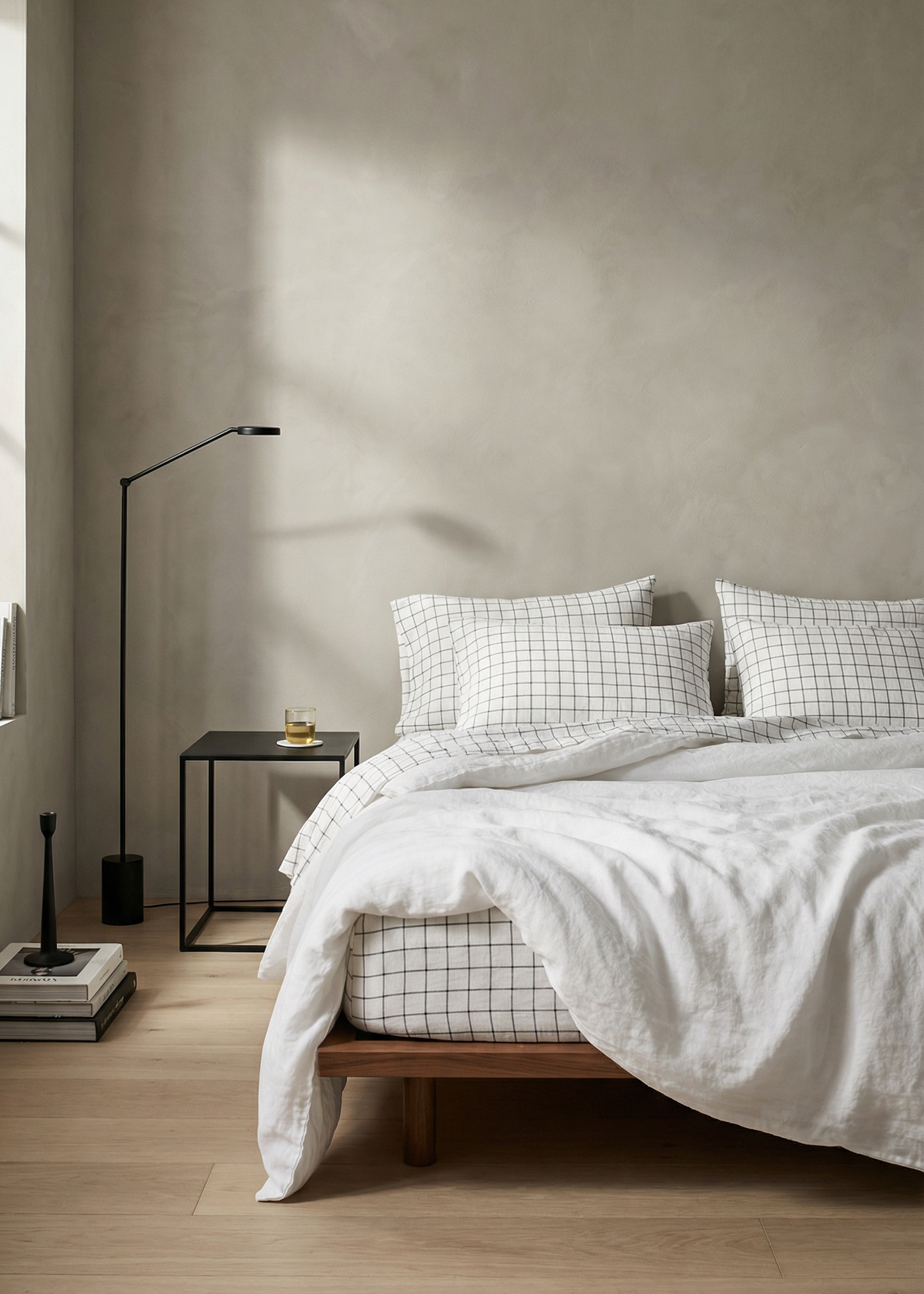 Minimalist bedroom with a bed, nightstands, and lamp against a plain wall.