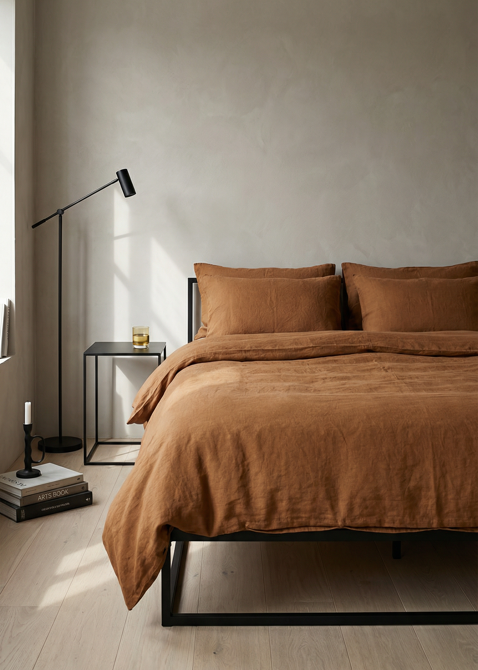Brown bedspread on a bed in a minimalistic bedroom with a lamp and side table.