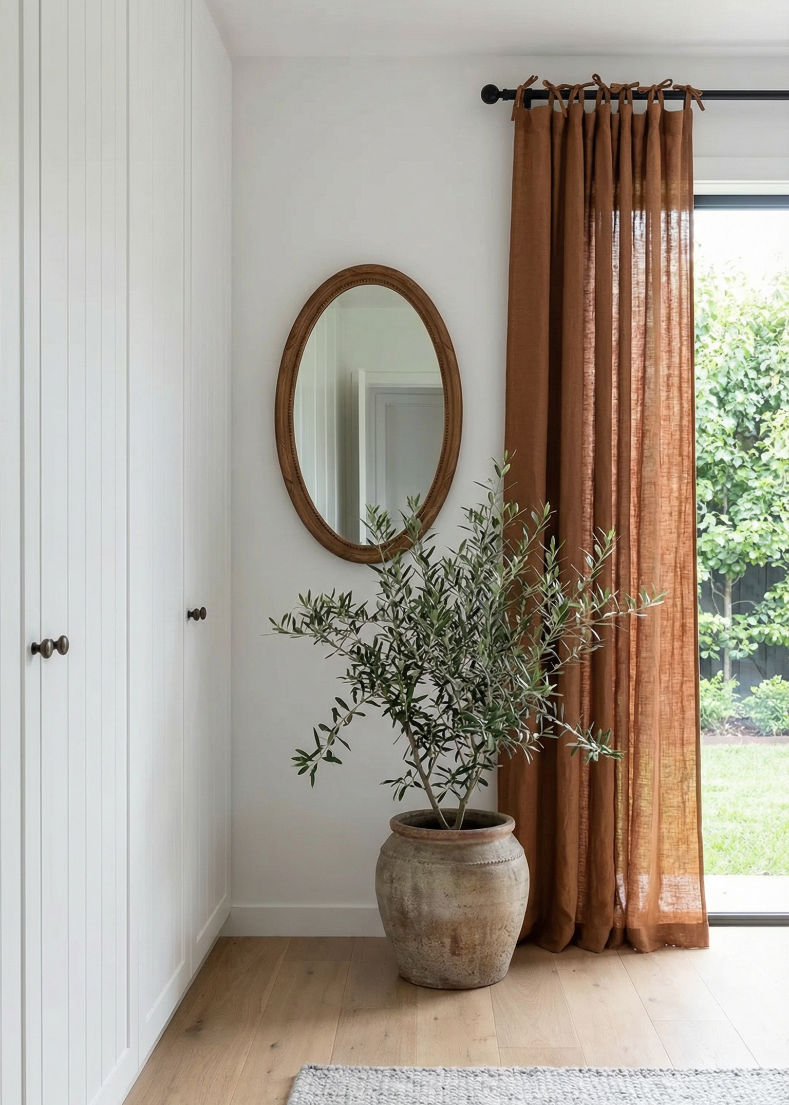Room interior with a plant, mirror, and curtains.