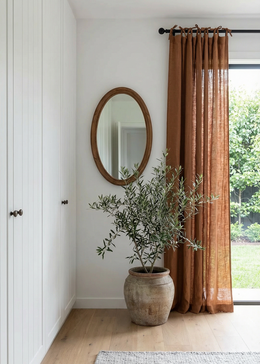 Room interior with a plant, mirror, and curtains.