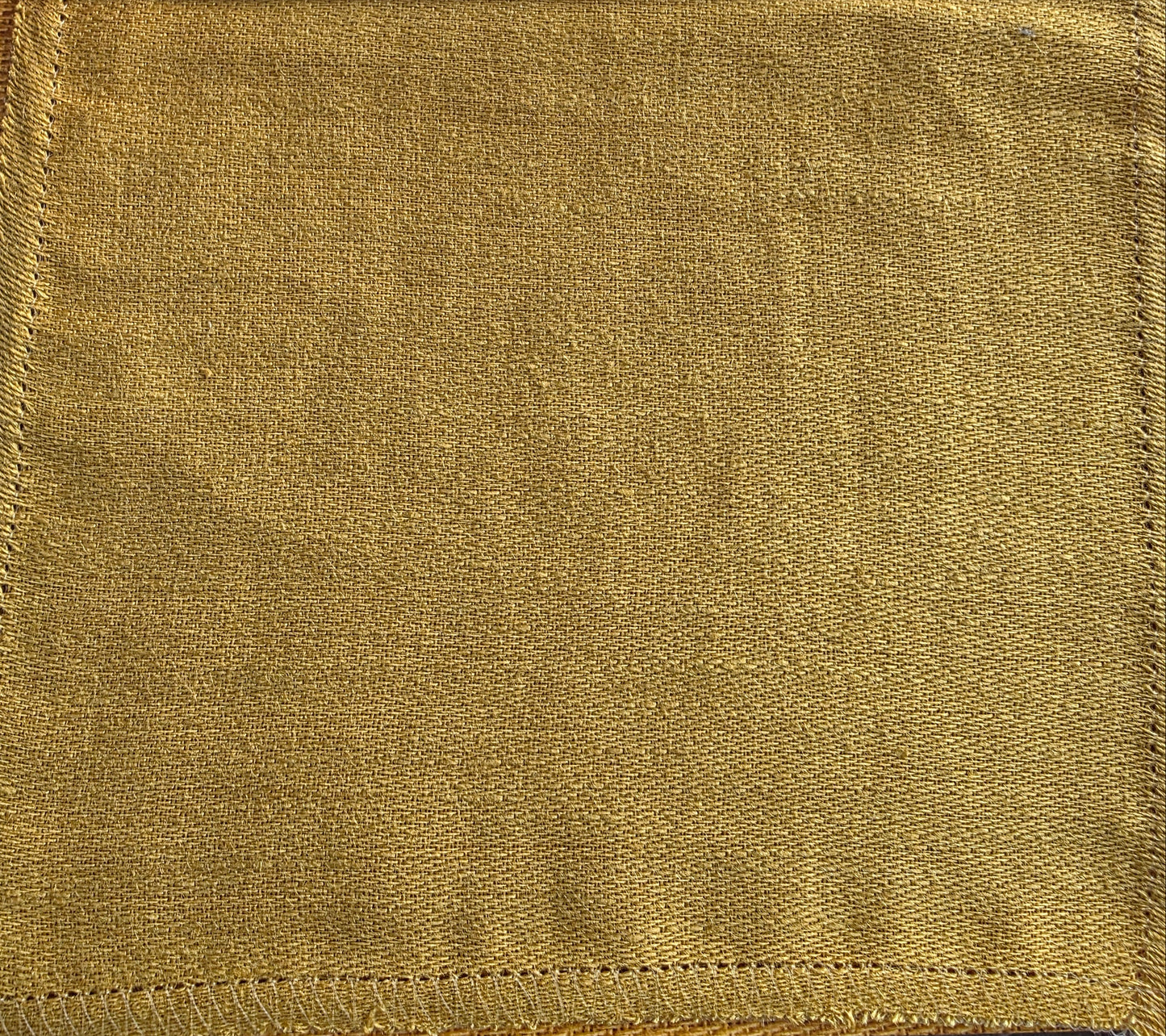 Gold fabric swatch held by a hand with 'Catherine Martin' branding.