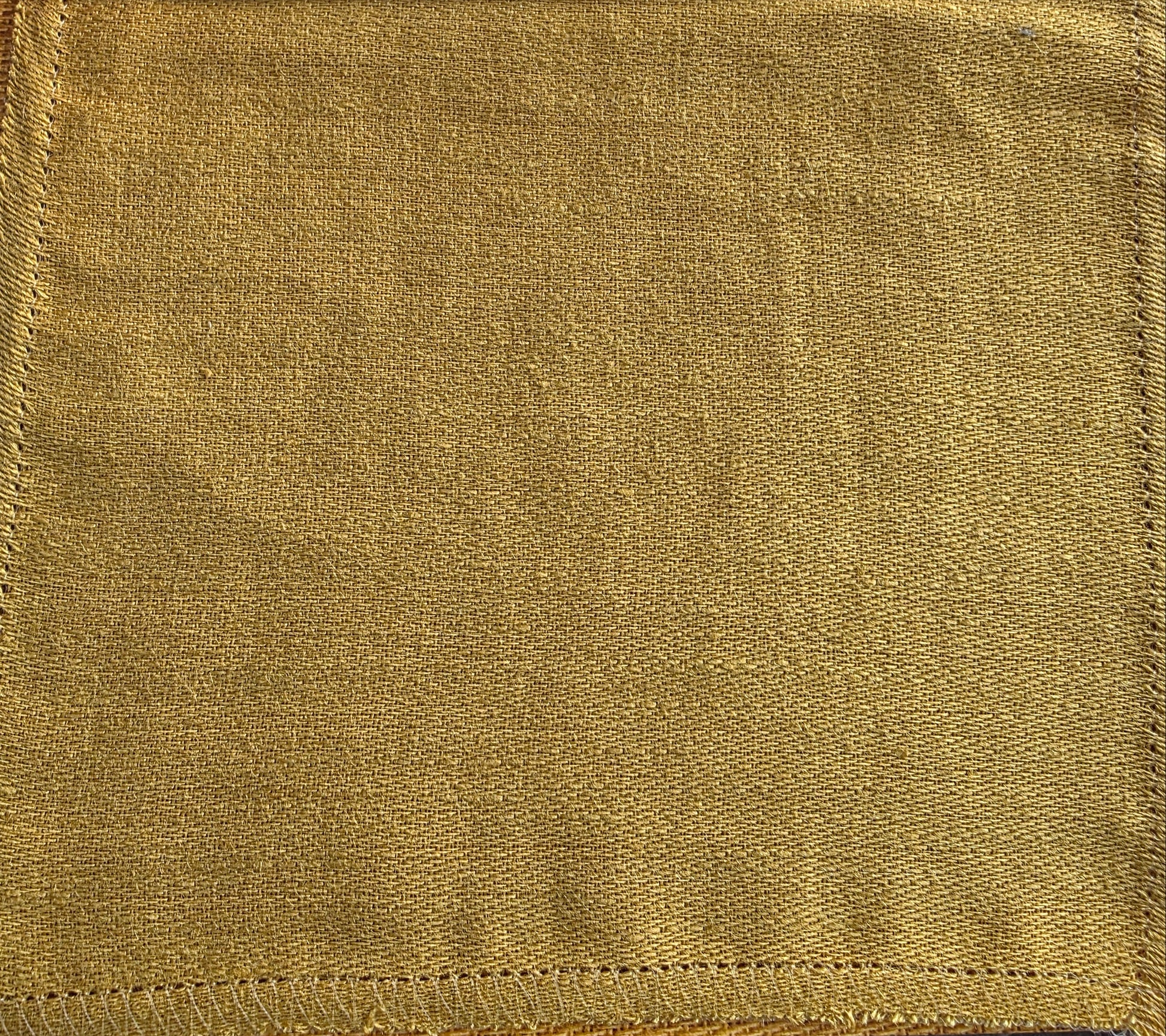 Gold fabric swatch held by a hand with 'Catherine Martin' branding.