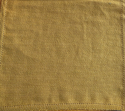 Gold fabric swatch held by a hand with 'Catherine Martin' branding.