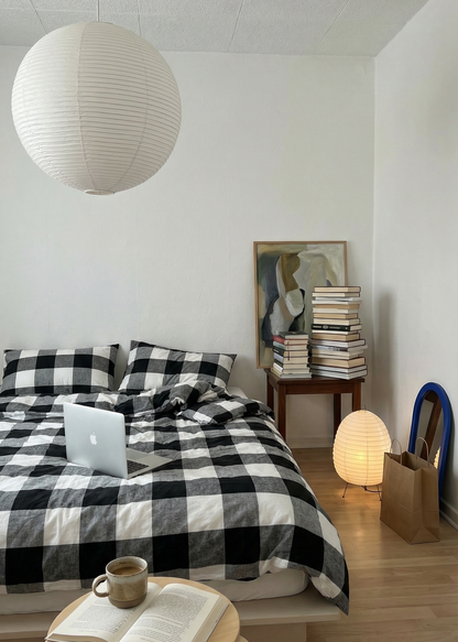 Modern bedroom with checkered bedspread, laptop, and books.