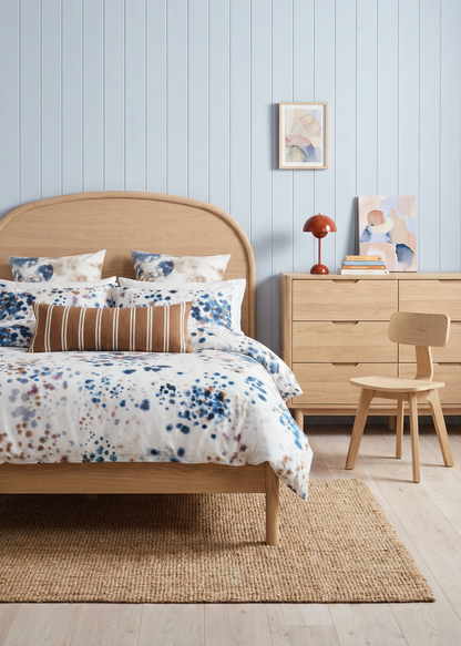 Bedroom with wooden bed, floral bedding, and light blue wall.