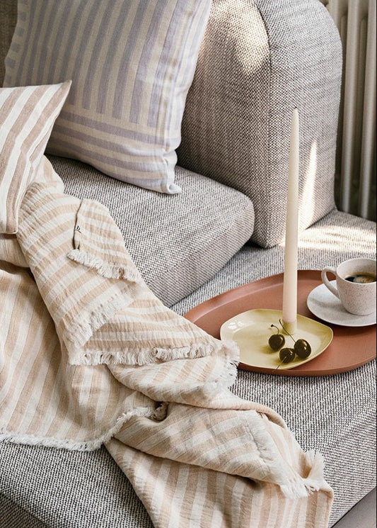 Cozy living room scene with a gray sofa, striped cushions, and a candle on a side table.
