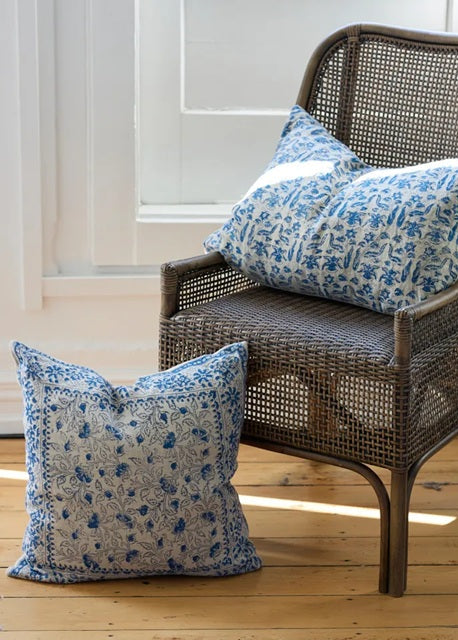 Wicker chair with blue patterned cushions on a wooden floor.