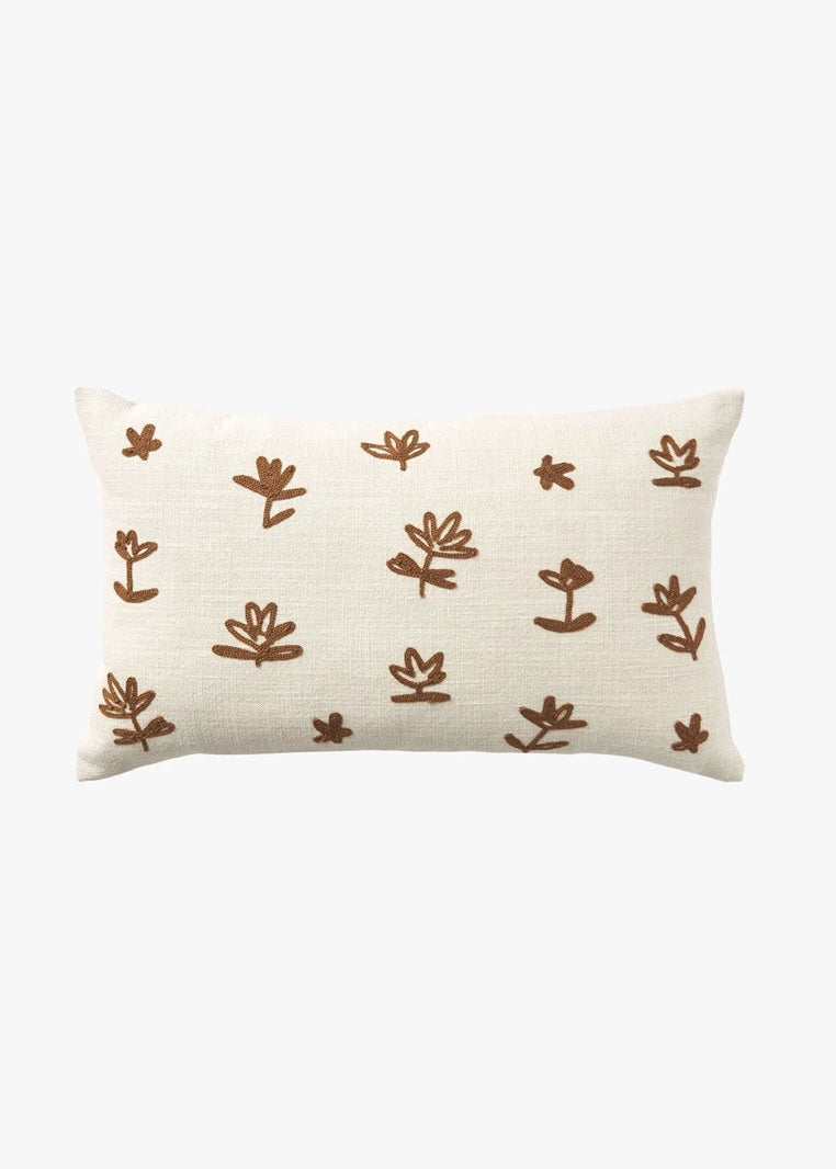 A rectangular cream-colored throw pillow with a textured linen-like fabric, decorated with a repeating pattern of hand-drawn brown botanical motifs, shown against a plain white background.