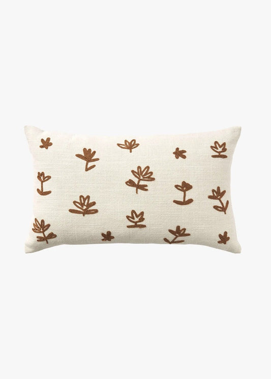 A rectangular cream-colored throw pillow with a textured linen-like fabric, decorated with a repeating pattern of hand-drawn brown botanical motifs, shown against a plain white background.