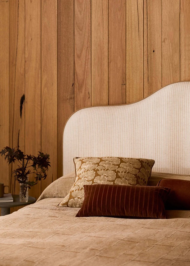 Bed with decorative pillows against a wooden wall