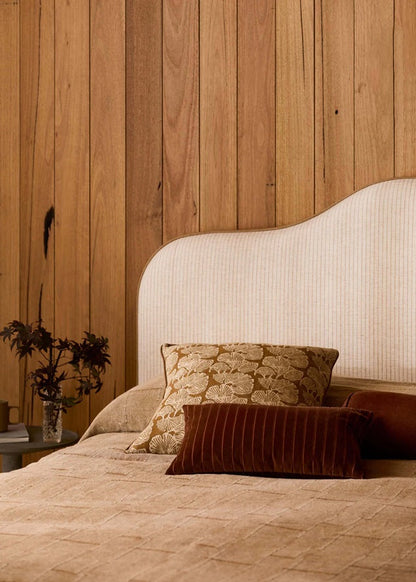 Bed with decorative pillows against a wooden wall