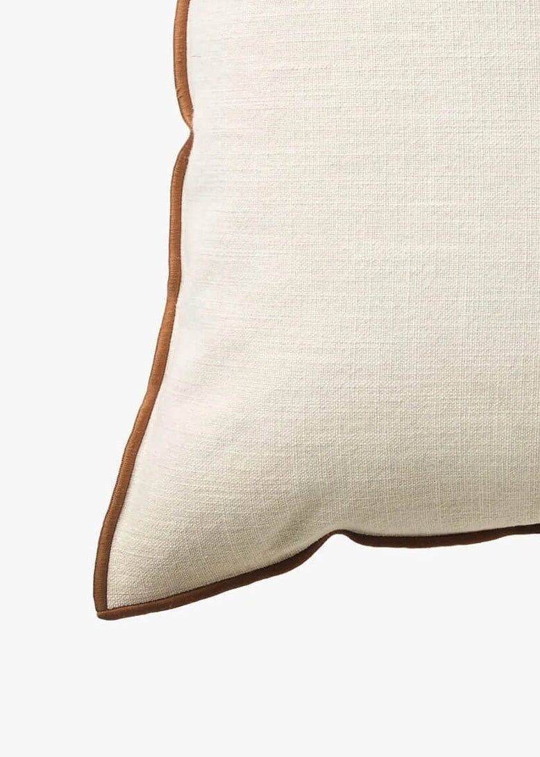 A square off-white linen throw pillow with a contrasting brown piped edge, shown against a plain white background.