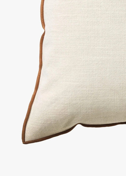 A square off-white linen throw pillow with a contrasting brown piped edge, shown against a plain white background.
